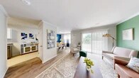 Located at 1204 Emily Lane in Carteret, NJ, this two-bedroom, two-bathroom two-story home is efficiently laid out across two well-proportioned floors. The main level opens into a bright, open-concept living, dining, and kitchen area finished with durable hardwood-style flooring and crown molding. The living room features a bold green accent wall, large sliding glass doors that flood the space with natural light, and direct access to a private balcony. Adjacent to the living area, the dining room makes a striking statement with a vivid blue accent wall, large window with elegant drape treatments, and a circular wood dining table. The kitchen is well-appointed with granite countertops, white upper cabinetry, gray lower cabinetry, subway tile backsplash, and a full suite of stainless steel appliances including a gas range and dishwasher. A dedicated laundry area and utility room add everyday convenience. Carpeted stairs with a warm wood handrail lead to the upper level, where both bedrooms are located. The generously sized primary bedroom features plush carpet, a teal accent wall, and ample natural light. The second bedroom is cozy and well-proportioned. Both bathrooms are clean and functional, with one featuring a tiled tub-shower combo with glass sliding doors. Three closets and hallway spaces complete the layout.