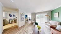 Located at 1204 Emily Lane in Carteret, NJ, this two-bedroom, two-bathroom two-story home is efficiently laid out across two well-proportioned floors. The main level opens into a bright, open-concept living, dining, and kitchen area finished with durable hardwood-style flooring and crown molding. The living room features a bold green accent wall, large sliding glass doors that flood the space with natural light, and direct access to a private balcony. Adjacent to the living area, the dining room makes a striking statement with a vivid blue accent wall, large window with elegant drape treatments, and a circular wood dining table. The kitchen is well-appointed with granite countertops, white upper cabinetry, gray lower cabinetry, subway tile backsplash, and a full suite of stainless steel appliances including a gas range and dishwasher. A dedicated laundry area and utility room add everyday convenience. Carpeted stairs with a warm wood handrail lead to the upper level, where both bedrooms are located. The generously sized primary bedroom features plush carpet, a teal accent wall, and ample natural light. The second bedroom is cozy and well-proportioned. Both bathrooms are clean and functional, with one featuring a tiled tub-shower combo with glass sliding doors. Three closets and hallway spaces complete the layout.