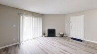 Located at 711 Farmhurst Dr in Charlotte, NC, this one-bedroom, one-bathroom unit offers a practical and comfortable layout across a single floor. The living room is bright and inviting, highlighted by a classic fireplace and large sliding glass doors with vertical blinds that allow generous natural light to fill the space. Light-toned luxury vinyl plank flooring runs through the main living areas, creating a clean and cohesive look. The kitchen flows directly from the living room and features dark navy cabinetry, light countertops, a full-size refrigerator, and a single-basin sink — providing efficient use of the available space. The bedroom is generously sized with soft carpeting underfoot, a textured ceiling, dual closets offering ample storage, and corner windows that bring in natural light. The bathroom is straightforward and functional, featuring a shower/tub combination. A dedicated laundry area includes washer and dryer hookups along with overhead wire shelving for added storage convenience. Neutral wall tones and consistent finishes throughout give the unit a cohesive, move-in-ready feel well-suited for comfortable everyday living.