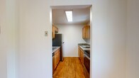 Located at 42 Rosilia Lane in Fishkill, NY, this single-floor unit offers a well-organized layout with distinct living, sleeping, and kitchen areas connected by a hardwood-style floored corridor. The entry door features brass hardware and opens into a central hallway, where a circuit panel is conveniently accessible.

The kitchen is a functional galley-style space illuminated by a skylight overhead, which fills the room with natural light throughout the day. Warm-toned wood cabinetry lines both walls, complemented by granite countertops, a stainless steel undermount sink, and stainless steel appliances including a refrigerator and dishwasher. The hardwood-style flooring continues throughout this area, adding warmth and cohesion.

The living area is generously proportioned, featuring plush carpeting, baseboard heating, and a sliding glass door that opens to a private balcony with views of surrounding greenery. The bedroom areas are also carpeted and bright, each benefiting from windows that bring in natural light. One bedroom includes a sliding closet, providing practical storage. A bathroom with clean white fixtures and wood-look flooring completes the layout, positioned conveniently off the main hallway.