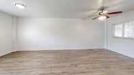 Located at 227 S Armenia Ave in Tampa, FL, this single-story, 2-bedroom, 1-bathroom unit offers a thoughtfully arranged layout that makes efficient use of its compact footprint. Consistent wood-look luxury vinyl flooring runs throughout the main living areas and bedrooms, creating a cohesive, clean aesthetic complemented by crisp white walls and bright white baseboards.

The combined living and dining area is an open, well-lit space featuring a ceiling fan with light fixture and windows fitted with blinds that allow natural light to filter in. The kitchen transitions directly from this area and is equipped with white cabinetry, dark countertops, stainless steel appliances including a refrigerator and electric range, an overhead exhaust hood, and tile flooring.

Both bedrooms continue the wood-look flooring and include ceiling fans. The primary bedroom provides a comfortable footprint with a closet accessible through the hallway. The second bedroom features a window with outdoor views and ample natural light.

The bathroom is finished with large-format travertine-style wall tiles surrounding a soaking tub and shower combination, with a built-in niche for added functionality. A dedicated laundry area and connecting hallway complete the unit's practical layout.