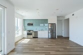 Located at 2277 Harbor Boulevard in Costa Mesa, California, this contemporary 2-bedroom, 2-bathroom residence offers a thoughtfully designed single-floor layout with clean lines and modern finishes throughout. Light-toned hardwood flooring flows seamlessly across the entire space, creating a bright and cohesive aesthetic.

The open-concept kitchen and living area serves as the heart of the home. The kitchen is outfitted with stainless steel appliances—including a gas range, built-in microwave, dishwasher, and a large French door refrigerator—complemented by sleek white lower cabinetry, sage-toned upper cabinets, and a light glass tile backsplash. An in-unit washer and dryer are conveniently tucked nearby.

The spacious primary bedroom features sliding glass doors that open to a private balcony with views of palm trees and the surrounding neighborhood, flooding the room with natural light. A ceiling fan adds comfort, and a walk-in closet with built-in shelving and hanging rods provides ample storage. The second bedroom includes mirrored sliding closet doors and a large window framing outdoor views.

Both bathrooms are well-appointed; one features a tub-shower combo enclosed by frameless glass doors and accented with elegant stone-look tile surround. Two hallways connect the rooms efficiently, completing this polished and functional residence.
