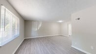 Located at 2751 Hammondton Road in Marietta, GA, this two-story home offers 3 bedrooms and 3 bathrooms across a well-organized floor plan. The main level houses the living room and kitchen, while the upper floor is dedicated to the bedrooms and additional bathrooms, providing a clear separation between living and sleeping areas.

The spacious living room features light gray wood-look flooring, neutral beige walls, and a textured ceiling, creating a clean and versatile space. A louvered utility closet door adds a practical touch to this open area. The kitchen is equipped with rich cherry wood cabinetry, granite-style countertops, a gas range, and stainless steel appliances, including a full-size refrigerator, all set over matching light wood-look flooring.

The bedrooms are carpeted in a warm beige tone and are finished with the same neutral wall palette. The generously sized primary bedroom includes a walk-in closet with wire shelving for ample storage. Secondary bedrooms feature windows with blinds that allow natural light. The hallways are finished with the same light wood-look flooring seen on the main level, maintaining visual consistency throughout.

The bathrooms include tiled tub-shower combinations, granite-top vanities with wood cabinetry, and chrome fixtures, offering clean and functional design throughout.