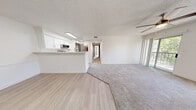 Located at 13150 Wenonah Ave SE in Albuquerque, New Mexico, this single-floor, three-bedroom, two-bathroom home offers a practical and well-appointed layout. The open-concept kitchen and living area serves as the heart of the home, featuring light wood-style flooring in the kitchen that transitions to plush carpet in the living room. The kitchen is outfitted with two-tone cabinetry — white upper cabinets paired with gray lower cabinets — complemented by white quartz countertops, a stainless steel sink with a modern faucet, and a full suite of stainless steel appliances including a refrigerator, range with over-the-range microwave, and dishwasher. A peninsula counter provides additional prep space and casual seating potential. The living area benefits from natural light via a sliding glass door. The three bedrooms are carpeted and feature textured ceilings and ceiling fans, with the primary bedroom offering a generous footprint and closet access. Both bathrooms are finished in white tile with tub/shower combinations and wood-style flooring. A dedicated closet space houses a stacked washer and dryer unit, adding notable convenience. The home presents a clean, neutral palette throughout.