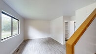 Located at 410 W Cherry St in Mount Pleasant, Michigan, this two-story unit offers four bedrooms and one bathroom across two well-proportioned floors. The main level features a bright living room with durable hardwood-style flooring and a wood-railed staircase leading to the upper level. The galley-style kitchen is equipped with warm wood cabinetry, granite-look countertops, a double stainless steel sink, and black appliances including a range and refrigerator. A convenient stacked washer and dryer unit is integrated directly into the kitchen area, adding practical in-unit laundry access. The full bathroom includes a tub-shower combination with clean white tile surround and chrome fixtures. The four bedrooms are spread across both floors, each featuring the same rich hardwood-style flooring, crisp white walls, and clean white trim. Several bedrooms offer views of the surrounding greenery through large windows that allow natural light to fill the rooms. A connecting hallway on the upper level links the bedrooms efficiently. Throughout the unit, the consistent flooring and neutral color palette create a cohesive and clean aesthetic, making the space adaptable for a variety of living arrangements.