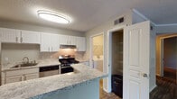 Located at 231 Calibre Chase Dr in Raleigh, NC, this single-floor residence offers a well-designed layout with thoughtful updates throughout. The kitchen is a standout feature, showcasing crisp white shaker-style cabinetry, granite-look countertops, a stainless steel gas range, and a peninsula with bar seating that opens toward the main living area — ideal for both everyday meals and entertaining. Adjacent to the kitchen is a dedicated pantry closet with wire shelving for organized storage, as well as direct access to an in-unit laundry room, adding everyday convenience. The living room is bright and welcoming, with large windows that invite natural light, a wood-burning fireplace with a classic mantel, and sliding glass doors leading to an outdoor space. Rich, dark-toned wood-style flooring runs throughout the main living areas, complemented by crown molding for an added touch of character. The bedroom is generously sized, finished with plush carpet and a window that frames natural greenery outside. The bathroom features a white vanity with granite-look countertops, a large wall mirror, and hardwood-style flooring, maintaining the cohesive design language of the home. Textured ceilings are present throughout, and the neutral color palette creates a calm, versatile ambiance across every room.