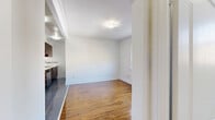 Located at 1660 Bathurst Street in Toronto's Forest Hill South neighbourhood, this one-bedroom, one-bathroom unit offers a functional and well-appointed layout across a single floor. The combined kitchen and living area forms the heart of the space, where rich hardwood flooring transitions into a tiled kitchen zone. The kitchen is outfitted with dark espresso cabinetry reaching toward the ceiling, white quartz countertops, a classic subway tile backsplash, and a full suite of stainless steel appliances including a refrigerator, stove, over-the-range microwave, and dishwasher. The living area is bright and open, featuring crown moulding and a window that draws in natural light. The bedroom is a well-proportioned private retreat with warm hardwood floors, a window with a street-facing view, classic white baseboards, and a traditional cast-iron radiator that adds a charming, vintage character. The bathroom is clean and efficiently designed, featuring large-format taupe wall tiles surrounding a soaking tub-shower combination, white tile flooring, and a small window that provides natural ventilation and light. A hallway connects the rooms, completing this practical and characterful urban home.