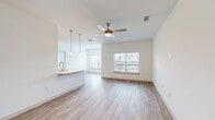 Located at Grande Dunes N Village Blvd in Longs, South Carolina, this one-bedroom, one-bathroom residence delivers a thoughtfully designed single-floor layout with contemporary finishes and a clean, neutral aesthetic throughout. The open-concept kitchen and living area serves as the heart of the home, featuring warm wood-look luxury vinyl plank flooring, crisp white walls, and a ceiling fan with light fixture. The kitchen is well-appointed with gray shaker-style cabinetry, white quartz countertops, a peninsula with an undermount sink, subway tile backsplash, and a full suite of stainless steel appliances including a range, microwave, refrigerator, and dishwasher. Pendant lighting above the peninsula adds a modern touch. The living room receives generous natural light through large windows with views of the surrounding community. The spacious bedroom is finished with plush wall-to-wall carpeting, a ceiling fan, and a bright window, offering a comfortable retreat. A dedicated closet provides organized storage. The bathroom features wood-look flooring and a gray vanity with brushed gold hardware. A dedicated laundry room houses an in-unit washer and dryer with overhead shelving for added convenience. Clean lines and a bright, move-in-ready condition define this well-rounded residence.