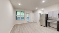 Located at 2050 Wood Duck Ct in Franklin, TN, this single-floor residence offers a well-designed 2-bedroom, 3-bathroom layout that balances modern finishes with practical, accessible living. The open kitchen is outfitted with gray shaker-style cabinetry, granite-look countertops, light wood-tone luxury vinyl plank flooring, and black appliances including a gas range, dishwasher, microwave, and stainless steel refrigerator — all illuminated by recessed lighting. The adjacent living area continues the light flooring and features a door providing direct outdoor access, allowing natural light to fill the space. The bedrooms are carpeted for comfort, with one bedroom offering a ceiling fan and a window with views of the surrounding greenery. A walk-in closet with wire shelving adds practical storage. The three bathrooms feature granite-topped vanities and light vinyl plank flooring; notably, one bathroom is equipped with ADA-compliant accessibility features including grab bars and a roll-under vanity. Throughout the residence, a neutral color palette of whites and warm grays creates a clean, cohesive aesthetic well-suited for a variety of living arrangements.