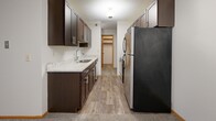Located at 10641 Greenbrier Rd in Minnetonka, MN, this one-bedroom, one-bathroom residence offers a well-organized single-floor layout designed for comfortable everyday living. The open-concept living, dining, and kitchen area forms the heart of the home, with the kitchen featuring dark espresso cabinetry, granite-look countertops, stainless steel appliances including a refrigerator and range, a double sink, and durable wood-style flooring. A chandelier above the dining area adds a touch of warmth to the space. The living room is carpeted and opens to a view of the outdoors, with a baseboard heating system running along the wall. A dedicated laundry area with washer and dryer is conveniently tucked within the unit alongside open shelving storage. The bedroom offers comfortable proportions, plush carpet, a window with natural light and outdoor views, baseboard heating, and a mirrored sliding-door closet with built-in shelving. A second closet provides additional storage. The bathroom is clean and functional, featuring a full tub-shower combination with tiled surround, a toilet, and classic white tile flooring. A textured ceiling is present throughout. This residence offers a practical and comfortable layout in a well-established Minnetonka location.