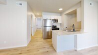 Located at 1056 W 1700 S in Salt Lake City, Utah, this two-story home offers a practical and modern layout across two well-proportioned floors. The main level features light wood-look flooring throughout, a bright kitchen equipped with stainless steel appliances, white shaker-style cabinetry, light stone countertops, a double-basin sink with a matte black faucet, and a peninsula that adds prep space and flow. The open sightlines from the kitchen extend down a clean hallway lined with panel doors leading to additional rooms and a utility area. A one-car garage adds convenience on this level. The bathrooms are finished with white vanities, matte black hardware, large mirrors, and light wood-look flooring, with one bathroom featuring a full tub/shower combination. The upper floor houses the bedrooms, including a generously sized primary bedroom, along with two additional carpeted bedrooms, each with windows that bring in natural light and sizable closets with sliding panel doors. With six closets distributed throughout, storage is abundant. The textured ceilings, neutral color palette, and consistent black hardware accents tie the home together with a clean, contemporary aesthetic.