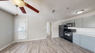 Located in Acworth, GA, this one-bedroom, one-bathroom residence offers a well-organized layout across a single floor. The open-concept kitchen and living area forms the heart of the home, featuring light gray wood-look flooring, a textured ceiling, and a ceiling fan that enhances air circulation. The kitchen is equipped with gray cabinetry, light countertops, and a full suite of black appliances including a refrigerator, electric range, microwave, and dishwasher — all arranged along a clean, functional galley-style wall. Natural light filters into the living area through a window adjacent to the balcony door, which provides access to a private outdoor space. The bedroom is a comfortable, well-proportioned room with a window fitted with blinds, continuing the same light wood-look flooring and neutral wall tones found throughout the home. Two closets offer ample storage. The bathroom features a full tub-shower combination with chrome fixtures and a clean white surround. A dedicated utility room rounds out the layout. The consistent use of neutral tones, modern hardware, and durable flooring gives the space a cohesive, move-in-ready aesthetic.