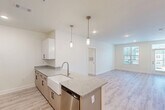 Located on Dellridge Place in Chattanooga, TN, this well-designed one-bedroom, one-bathroom unit offers a thoughtful, efficient layout with modern finishes throughout. The open-concept kitchen and living area serves as the heart of the home, featuring light wood-style flooring, crisp white cabinetry, granite countertops, and a peninsula island with a farmhouse sink and seating overhang. Stainless steel appliances — including a refrigerator, electric range, microwave, and dishwasher — complete the kitchen, while two stylish pendant lights add a refined touch overhead. The spacious bedroom is carpeted for comfort and includes a ceiling fan, a natural light-filled window with exterior views, and access to two closets, including a generous walk-in with wire shelving. The bathroom features light wood-style flooring, a clean and functional design, and a closet with built-in wire shelving conveniently accessible from the hallway. A dedicated laundry room houses a full-size washer and dryer along with overhead wire storage shelving. Neutral tones, recessed lighting, and consistent finishes create a bright, cohesive ambiance throughout this well-appointed Chattanooga residence.