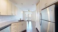 Located at 126 New Bern St in Charlotte, NC 28203, this 480-square-foot single-floor unit offers an efficient and well-appointed layout within the vibrant South End neighborhood. Rich, dark hardwood floors run throughout the entire space, creating a cohesive and polished aesthetic.

The galley-style kitchen is a functional highlight, featuring granite countertops, white shaker cabinetry extending to the ceiling, a white subway tile backsplash, and a full suite of stainless steel appliances including a refrigerator, electric range, microwave, and dishwasher. A peninsula with a sink adds counter space and casual dining potential.

The open living area is bright and airy, benefiting from large double French doors that lead to a balcony and an additional side window, allowing ample natural light to fill the room. A ceiling fan provides year-round comfort.

The bathroom is well-designed with granite countertops, white cabinetry, a framed mirror, and a full tiled soaking tub/shower combination with recessed lighting overhead. A dedicated closet provides essential storage. The unit also includes a keypad-entry front door for added security and convenience.