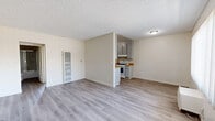 Located on Foothill Blvd in Tujunga, CA, this single-story, one-bedroom, one-bathroom unit offers a thoughtfully laid-out floor plan that makes efficient use of its space. The living room welcomes you with light gray laminate flooring, neutral beige walls, and a textured ceiling, with a window dressed in vertical blinds that allows natural light to brighten the room. A wall-unit air conditioner provides climate control. The open layout connects the living area to a designated dining space, which flows seamlessly toward the kitchen. The galley-style kitchen is well-appointed with gray cabinetry lining both walls, warm wood-toned countertops, a stainless steel sink, and a white gas range with overhead ventilation — all complemented by laminate flooring and ample upper and lower cabinet storage. The bedroom is a comfortable, carpeted retreat featuring a large window with sheer curtains that invite natural light, a sliding-door closet with a built-in hanging rod, and a textured ceiling. The full bathroom includes a single-sink vanity with storage drawers, a toilet, and a tub/shower combination enclosed by sliding glass doors, with wood-style flooring tying the space together. A hallway connects the main living areas to the bedroom and bathroom, completing this functional and tidy single-floor layout.
