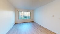 This one-bedroom, one-bathroom unit is located at 3630 Renton Ave S in Seattle's Rainier Valley neighborhood. The single-level layout makes efficient use of its intimate footprint, with light wood-tone flooring running throughout all rooms, creating a cohesive and clean aesthetic.

The entrance hall features a textured ceiling and a built-in closet, leading into the open kitchen and living area. The kitchen includes white cabinetry and a functional countertop layout that flows naturally into the living space, which is bathed in natural light from a large picture window overlooking lush greenery.

The bedroom is a comfortable, well-proportioned room featuring a sliding-door closet, a textured ceiling, and a window framing views of surrounding trees and landscaping — bringing a sense of calm and nature into the private retreat. A second closet provides additional storage in the hallway.

The bathroom is clean and straightforward, appointed with a full-size soaking tub and shower combination, a single vanity with white cabinetry, and a gold-framed mirror that adds a subtle accent. The overall palette throughout the unit is crisp white with warm wood tones, giving the space a bright, move-in-ready feel well-suited to efficient, comfortable urban living.