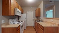 Located at 351 Peat Moss Dr in Columbus, OH 43235, this single-floor unit offers a functional and well-organized layout throughout. The galley-style kitchen is equipped with warm oak cabinetry, light countertops, hardwood-style flooring, and white appliances including a range, over-the-range microwave, refrigerator, and dishwasher. A utility door at the end of the kitchen provides added convenience.

The open living area is generously sized, featuring neutral-toned carpet, a textured ceiling, and sliding door access that brings in natural light. The space flows seamlessly into the rest of the unit, with clear sightlines toward the hallway and kitchen.

Multiple bedrooms feature plush carpeting, neutral wall tones, and windows with blinds that allow for natural light and outdoor views. Each bedroom includes a closet with built-in hanging rods, offering practical storage solutions.

Two full bathrooms serve the unit. One features a single-vanity with oak cabinetry, a large mirror, tile flooring, and a shower-tub combination. The second bathroom includes a similar vanity setup, tile flooring, and a glass-enclosed shower stall. Both bathrooms are finished in light, neutral tones that complement the overall aesthetic of the unit.