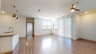This well-designed single-floor residence offers a clean, contemporary aesthetic throughout. The open-concept living area is anchored by warm wood-look flooring that flows seamlessly across the main spaces. Large windows and a sliding glass door fitted with vertical blinds allow abundant natural light to fill the room, complemented by a ceiling fan overhead for year-round comfort.

The kitchen is a standout feature, outfitted with crisp white cabinetry, granite countertops, and a full suite of stainless steel appliances including a refrigerator, electric range, microwave, and dishwasher. A herringbone-patterned tile backsplash adds a stylish touch, while a central island with pendant lighting above serves as both a prep area and casual gathering point.

The bedrooms are finished with plush neutral carpet and ceiling fans, each benefiting from natural light through blinds-fitted windows. Multiple bedrooms provide flexible living arrangements, with closet access visible in several rooms.

The bathrooms are thoughtfully appointed with granite-topped vanities, white cabinetry, and wood-look flooring. One bathroom features a walk-in glass-enclosed shower with tile surround, while another includes a tiled tub-shower combination. Brushed nickel fixtures and hardware provide a cohesive, modern finish throughout. The overall ambiance is bright, clean, and move-in ready.