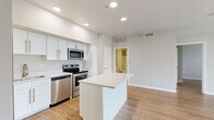 This well-appointed one-bedroom, one-bathroom residence in Loveland, Colorado offers a thoughtfully designed single-floor layout with a bright, open feel throughout. The heart of the home is the open-concept kitchen and living area, where a large white kitchen island serves as a central gathering point. The kitchen is outfitted with crisp white shaker cabinetry, light quartz countertops, and a full suite of stainless steel appliances, including a refrigerator, range, microwave, and dishwasher. Warm, light-toned hardwood-style flooring flows seamlessly across all living spaces, complementing the neutral gray and white color palette. The spacious living room receives generous natural light through a large sliding glass door and an adjacent window fitted with vertical blinds, offering views of the surrounding area. The bedroom is a comfortable, well-proportioned retreat featuring its own window with natural light and direct access to a closet. The bathroom is clean and functional, featuring a white vanity with quartz countertop, a tub-shower combination with tiled surround, and brushed nickel fixtures. A dedicated in-unit laundry area houses a full-size side-by-side washer and dryer with built-in shelving above. Recessed lighting and a neutral color scheme contribute to a modern, move-in-ready ambiance throughout.