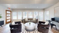 Located at 2604 Furrs St in Arlington, Texas, this single-floor space offers a thoughtfully designed open-plan layout that maximizes functionality and comfort. The kitchen is a standout feature, outfitted with rich dark espresso cabinetry, light quartz countertops, and a classic white subway tile backsplash. Stainless steel appliances — including a French door refrigerator with ice maker, built-in microwave, and dishwasher — deliver a sleek, modern aesthetic. A double-basin stainless steel sink and generous cabinetry provide ample storage and workspace. Wood-look plank flooring runs throughout, adding warmth and visual continuity between zones. The living area is bathed in natural light through a bank of large windows dressed with white horizontal blinds, offering views of the surrounding greenery. Recessed lighting complements the natural illumination overhead. A vaulted ceiling in an adjacent nook adds architectural character and an airy sense of openness, making the space feel larger than its footprint suggests. The neutral color palette of soft whites and warm wood tones creates a clean, inviting ambiance well-suited for both relaxation and productivity.