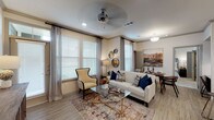 This thoughtfully designed single-floor residence offers an open-concept layout that seamlessly connects the living, dining, and kitchen areas. The living room is bright and inviting, benefiting from an abundance of natural light streaming through multiple large windows dressed with blinds and elegant drape panels. A ceiling fan, recessed lighting, and crown molding add refined detail to the space, which features durable wood-look flooring throughout the main areas.

The kitchen is a standout feature, showcasing dark espresso cabinetry, granite countertops, a large island with bar seating, stainless steel appliances, a tile backsplash, and pendant lighting overhead. Directly adjacent is a convenient built-in workspace complete with a granite-topped desk, storage cabinetry, and open display shelving — ideal for working from home.

The primary bedroom offers plush carpeting, generous natural light, and a walk-in closet. A second bedroom provides equal comfort with soft carpeting, bright windows, and ample space. The bathroom features wood-look flooring, dark vanity cabinetry with a granite countertop, and a combined tub and shower area.

Completing the home is a dedicated in-unit laundry area with full-size washer and dryer and wire shelving for added storage. The overall ambiance is warm, modern, and functional.