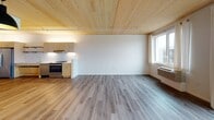 This thoughtfully designed single-floor unit showcases a warm, contemporary aesthetic defined by its standout natural wood-planked ceilings, which lend an inviting, cabin-inspired character throughout the main living spaces. The open-concept living and dining area is bright and generously proportioned, with light hardwood-style flooring underfoot and large windows and sliding glass doors that flood the interior with natural light and provide direct access to a private balcony with outdoor views.

The kitchen is efficiently laid out along one wall and features light wood cabinetry, stainless steel appliances including a range and dishwasher, a clean white tile backsplash, and under-cabinet lighting that highlights the streamlined countertops. Open shelving adds a modern touch to the cooking space.

The bedroom is a comfortable, quiet retreat with plush carpeting, a wood-paneled ceiling consistent with the rest of the unit, a wall sconce for ambient lighting, and a window offering views of the surrounding neighbourhood and greenery.

The bathroom is clean and functional, featuring warm wood-toned laminate flooring, white walls, a floating vanity with a wooden base, and a shower with a curtain enclosure. Grab bars and an accessible layout contribute to practical, inclusive design. Recessed lighting keeps the space bright and welcoming throughout.