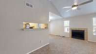 This single-floor residence offers a thoughtfully designed layout with a comfortable blend of functional spaces and inviting architectural details. The living room serves as the heart of the home, showcasing soaring vaulted ceilings, a ceiling fan, and a tile-surround fireplace that adds warmth and character. Soft carpeting runs throughout the living area, and a window brings in natural light alongside a view of the outdoors. A pass-through window connects the living area to the kitchen, creating an open, airy feel.

The galley-style kitchen is well-appointed with white cabinetry, granite-look countertops, stainless steel appliances including a refrigerator and dishwasher, and hardwood-style flooring. A dedicated in-unit laundry area is conveniently accessible directly from the kitchen.

The bedrooms are generously sized with plush carpeting and textured ceilings. One bedroom features direct access to a walk-in closet with built-in shelving. Both bathrooms are finished with granite-look vanity countertops, white cabinetry, tile-surround tub-shower combinations, and rich hardwood-style flooring. An additional room offers sliding glass door access to an outdoor balcony or patio, filling the space with natural light and providing a seamless indoor-outdoor connection.