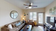 This single-story residence offers a thoughtfully designed layout with multiple rooms that balance comfort and functionality. The living area serves as the heart of the home, featuring rich hardwood-style flooring, a ceiling fan with integrated lighting, and multiple windows fitted with blinds that allow natural light to filter in. A glass-paneled door provides additional brightness and outdoor access. Decorative floating shelves and a large round mirror add character to the neutral-toned walls.

The kitchen is outfitted with dark cabinetry, granite-look countertops, stainless steel appliances including a full-size refrigerator and built-in microwave, and a black range. Track lighting overhead and hardwood-style flooring complete the space efficiently.

Both bedrooms feature plush carpeting and ceiling fans. The primary bedroom includes a walk-in closet and connects to a private bathroom with a tub/shower combination, dark vanity cabinetry, and hardwood-style flooring. The second bedroom, also carpeted, is served by a separate full bathroom also equipped with a tub/shower combo. Each bedroom benefits from natural light through blinded windows, creating a calm and comfortable atmosphere throughout.