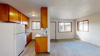 This efficiently designed single-floor unit offers a well-organized layout encompassing a combined dining room, kitchen, and living area, one bedroom, one bathroom, a hallway, and four closets providing generous storage throughout. The open-concept main living area features neutral-toned carpet in the living and dining zones, while the kitchen transitions to wood-look vinyl flooring. The kitchen is equipped with warm honey-toned wood cabinetry, a white refrigerator, an electric coil range with a countertop workspace, and a built-in sink — all illuminated by a window overlooking the outdoors. A textured ceiling runs throughout the unit, adding visual character. The living area is bright and airy, benefiting from two windows with wood-trimmed frames that draw in natural light and offer exterior views. The bedroom is a comfortable, carpeted retreat featuring a ceiling fan with light fixture, a large mirrored closet door, a window, and direct access to the hallway. The full bathroom includes a white soaking tub and shower combination with clean white surround panels, a toilet, and wood-look flooring. A baseboard heating system is also present in the kitchen area, ensuring year-round comfort throughout this functional and cohesive living space.