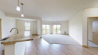 This 1,270-square-foot, single-floor condo at N72W13536 Lund Lane in Menomonee Falls, WI features 2 bedrooms, 2 bathrooms, and a thoughtfully designed open layout. The spacious living room is anchored by large sliding glass doors that open to a private balcony, flooding the carpeted space with natural light and providing pleasant outdoor views. The kitchen flows seamlessly from the living area and is equipped with rich dark wood cabinetry, stainless steel appliances including a refrigerator, electric range, and microwave, granite countertops, a breakfast bar peninsula, track lighting, and light wood-style flooring. A pantry provides additional storage convenience. The primary bedroom spans 170 square feet with a large window and plush carpeting, accompanied by a dedicated en-suite bathroom featuring a walk-in shower with glass doors, a double-sink vanity with dark wood cabinetry, and light wood-style flooring. The second bedroom also offers carpeting and a window with outdoor views. The second bathroom includes a full soaking tub and shower combo with grab bars, dark wood cabinetry, and matching flooring. Two closets, including a walk-in with wire shelving, round out the unit's ample storage throughout.