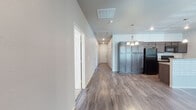 This single-floor residence offers a clean, modern layout with a neutral color palette and quality finishes throughout. The open-concept living and kitchen area serves as the heart of the home, featuring rich wood-look flooring, recessed lighting, and a ceiling fan that enhances air circulation. The kitchen is equipped with dark espresso cabinetry, granite-look countertops, black appliances including a range, over-the-range microwave, and refrigerator, as well as a peninsula island illuminated by pendant lighting — ideal for casual dining or meal prep.

A long, well-lit hallway connects the main living areas to the private quarters, where multiple bedrooms feature plush wall-to-wall carpeting, ceiling fans with light fixtures, and natural light from windows fitted with horizontal blinds. Each bedroom includes a dedicated closet, providing ample storage space.

The bathrooms are finished with crisp white tub-shower combinations featuring built-in shelving, chrome hardware, and wood-look flooring that ties cohesively to the rest of the home. The overall design emphasizes functionality and a clean aesthetic, making this a comfortable and practical living space suited for a variety of lifestyles.
