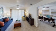 Located at 3605 Landings Way Dr in Tampa, FL, this single-floor residence offers a thoughtfully designed layout that balances functionality and comfort throughout its living spaces.

The kitchen is equipped with white cabinetry, white appliances including a refrigerator and range, and a dark granite-style countertop that wraps around a peninsula breakfast bar. The bar seating with black metal stools provides a casual dining option, while tile backsplash and wood-look flooring add a polished finish to the space.

The living area is generously proportioned, featuring plush carpeting, a ceiling fan, and wide sliding glass doors dressed with vertical blinds that allow ample natural light to fill the room. An adjacent flex space, visible through a wide doorway, offers additional room that can serve as a dining or secondary sitting area, also with carpeting and a ceiling fan.

The bedroom is a calm, well-sized retreat with carpeted flooring, a ceiling fan, and a window with vertical blinds that provides natural light. The room offers sufficient wall space for large-scale artwork and accommodates a sitting area.

The bathroom is clean and functional, featuring a white vanity with under-cabinet storage, a large mirror with overhead lighting, wood-look flooring, and a shower-tub combination. The overall ambiance of this residence is bright, neutral, and move-in ready.