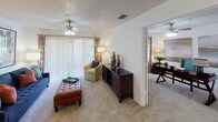Located at 3605 Landings Way Dr in Tampa, FL, this single-floor residence offers a thoughtfully designed layout that balances functionality and comfort throughout its living spaces.

The kitchen is equipped with white cabinetry, white appliances including a refrigerator and range, and a dark granite-style countertop that wraps around a peninsula breakfast bar. The bar seating with black metal stools provides a casual dining option, while tile backsplash and wood-look flooring add a polished finish to the space.

The living area is generously proportioned, featuring plush carpeting, a ceiling fan, and wide sliding glass doors dressed with vertical blinds that allow ample natural light to fill the room. An adjacent flex space, visible through a wide doorway, offers additional room that can serve as a dining or secondary sitting area, also with carpeting and a ceiling fan.

The bedroom is a calm, well-sized retreat with carpeted flooring, a ceiling fan, and a window with vertical blinds that provides natural light. The room offers sufficient wall space for large-scale artwork and accommodates a sitting area.

The bathroom is clean and functional, featuring a white vanity with under-cabinet storage, a large mirror with overhead lighting, wood-look flooring, and a shower-tub combination. The overall ambiance of this residence is bright, neutral, and move-in ready.