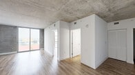 Located on the eighth floor in the heart of Miami's Brickell neighborhood, this one-bedroom, one-bathroom residence showcases a contemporary industrial aesthetic defined by exposed concrete ceilings, crisp white walls, and warm wood-look flooring throughout. The open-concept living area is bathed in natural light, with floor-to-ceiling windows and a sliding glass door framing sweeping views of the Miami skyline and surrounding greenery. The kitchen is thoughtfully appointed with light wood cabinetry, white countertops, a full suite of stainless steel appliances including a refrigerator, range, microwave, and dishwasher, and track lighting mounted to the exposed concrete ceiling above. The bedroom is a comfortable, well-proportioned retreat featuring expansive floor-to-ceiling windows that flood the room with daylight and offer elevated city views. A dedicated closet provides ample storage. The bathroom features a soaking tub with tiled surround, a wood-toned vanity with white countertop, and wood-look tile flooring. An in-unit washer and dryer add everyday convenience. The unit's industrial-modern design, elevated position, and central Brickell location make it a distinctive Miami residence.