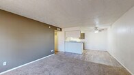 Located at 4901 Fourth Street in Lubbock, Texas, this two-bedroom, two-bathroom unit offers a practical and comfortable single-floor layout. The living room provides a generous open feel, featuring plush carpeting, neutral walls, a textured ceiling, and a window that allows natural light to filter in. An accent wall in a warm brown tone adds a touch of character to the space, which opens directly toward the kitchen area. The kitchen is laid out in a galley style, equipped with ample cabinetry in a warm taupe finish, white appliances including a range, dishwasher, and refrigerator, and wood-look flooring that extends into the adjoining areas. The two bedrooms are carpeted and well-proportioned, with the primary bedroom offering notable space and a closet with built-in shelving for organized storage. Natural light enters each bedroom through window treatments. The two bathrooms are functional and clean; one features a tiled tub-and-shower combination, while the other includes overhead cabinetry for additional storage and wood-look flooring. Throughout the unit, the design is straightforward and neutral, making it easy to personalize.