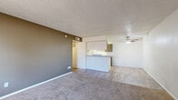 Located at 4901 Fourth Street in Lubbock, Texas, this two-bedroom, two-bathroom unit offers a practical and comfortable single-floor layout. The living room provides a generous open feel, featuring plush carpeting, neutral walls, a textured ceiling, and a window that allows natural light to filter in. An accent wall in a warm brown tone adds a touch of character to the space, which opens directly toward the kitchen area. The kitchen is laid out in a galley style, equipped with ample cabinetry in a warm taupe finish, white appliances including a range, dishwasher, and refrigerator, and wood-look flooring that extends into the adjoining areas. The two bedrooms are carpeted and well-proportioned, with the primary bedroom offering notable space and a closet with built-in shelving for organized storage. Natural light enters each bedroom through window treatments. The two bathrooms are functional and clean; one features a tiled tub-and-shower combination, while the other includes overhead cabinetry for additional storage and wood-look flooring. Throughout the unit, the design is straightforward and neutral, making it easy to personalize.
