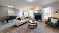 This thoughtfully designed single-floor residence offers a comfortable and functional layout across several well-defined living spaces. The living room serves as the heart of the home, featuring plush carpeting, abundant natural light from multiple windows with plantation shutters, and a handsome fireplace framed by a dark wood mantel. The open layout connects seamlessly to a dining area and a fully equipped kitchen outfitted with dark cabinetry, granite-style countertops, stainless steel appliances including a French door refrigerator, and a peninsula with bar seating—ideal for casual dining or entertaining. The primary bedroom is generously proportioned, featuring carpet flooring, a ceiling fan, and ample natural light. It connects to a well-appointed bathroom with dark vanity cabinetry, a large mirror, tile flooring, and access to a spacious walk-in closet with built-in shelving. A secondary bedroom provides additional flexibility, currently utilized as a home office, with carpeted floors, a bright window, and tasteful wall accents. Throughout the residence, neutral tones and consistent finishes create a cohesive and inviting ambiance suited for comfortable everyday living.