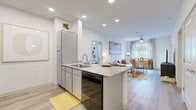 This 2-bedroom, 2-bathroom residence offers a bright, modern layout designed for comfortable everyday living. The open-concept kitchen and living area serves as the heart of the home, featuring light wood-style flooring, recessed lighting, and a peninsula with granite countertops and bar seating — ideal for casual dining or entertaining. The kitchen is equipped with stainless steel appliances, gray cabinetry, and ample counter space. The adjoining living area is bathed in natural light from large windows dressed with blinds and curtains, and includes a ceiling fan overhead. A dedicated dining nook tucks neatly into the living space, adding functional versatility.

Both bedrooms are carpeted for comfort and receive generous natural light through sizable windows. Each bedroom is supported by its own closet and full bathroom. The bathrooms feature wood-style flooring, granite-topped vanities, and clean, contemporary finishes. One bathroom offers convenient direct access to its adjacent walk-in closet.

Throughout the residence, a clean white color palette, consistent flooring, and thoughtful spatial planning create a cohesive and airy ambiance. The layout flows naturally from room to room, making efficient use of every square foot.