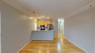 This single-floor residence offers a well-organized layout with a clear separation between living and private spaces. The open-concept main living area is anchored by a peninsula-style kitchen featuring light wood cabinetry, white countertops, and a full suite of stainless steel appliances, including a refrigerator, electric range, and over-the-range microwave. Recessed lighting and crown molding add a polished finish to the space, while light hardwood flooring extends throughout the main living areas, reflecting natural light and contributing to a bright, airy atmosphere.

The bedrooms are carpeted for comfort and receive natural light through large windows with views of the surrounding exterior. One bedroom features a spacious walk-in closet fitted with wire shelving, providing ample storage. The full bathroom includes a soaking tub with a shower surround, a vanity, and tile flooring. An additional half bath with tile flooring serves as a convenient powder room. A dedicated laundry room houses a full-size washer and dryer alongside the unit's mechanical systems. The overall aesthetic is clean and neutral throughout.