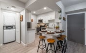 This 2-bedroom, 2-bathroom residence at 171 E St offers a thoughtfully designed single-floor layout that blends modern finishes with a warm, inviting atmosphere. The open-concept living, dining, and kitchen area serves as the heart of the home, featuring light wood-look flooring that flows seamlessly throughout the main space. A vaulted ceiling detail above the kitchen adds architectural interest and an airy sense of volume to the area.

The kitchen is well-appointed with crisp white shaker cabinetry, granite countertops, a tile mosaic backsplash, and a full suite of stainless steel appliances. A breakfast bar with barstool seating provides a casual dining option directly adjacent to the kitchen. The living room is bright and welcoming, benefiting from recessed lighting and a sliding glass door that invites natural light and offers outdoor access.

Both bedrooms are carpeted and generously proportioned, each featuring windows that bring in natural light and outdoor views. The two bathrooms are finished consistently with white cabinetry, granite vanity tops, and shower-tub combinations, maintaining a clean and cohesive aesthetic throughout. The overall design palette of neutral tones and modern fixtures creates a comfortable, move-in-ready environment well-suited for everyday living.