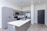 Located in American Fork, Utah, this thoughtfully designed 2-bedroom, 2-bathroom unit offers a clean, contemporary aesthetic throughout its single-floor layout. The open-concept living and kitchen area serves as the heart of the space, featuring light wood-look flooring, recessed lighting, and an abundance of natural light from large windows. The modern kitchen is equipped with sleek gray flat-panel cabinetry, stainless steel appliances including a range and built-in microwave, and a generous center island with a white quartz countertop and undermount sink — ideal for both cooking and casual dining.

Both bedrooms are carpeted and generously proportioned, with ceiling fans, recessed lighting, and large windows that frame views of the surrounding area. The spacious primary bedroom connects to a dedicated bathroom, while the second bedroom also benefits from convenient bathroom access. Each bedroom includes its own closet, with one featuring a walk-in closet complete with built-in shelving and hanging rods.

The two bathrooms are finished with white quartz vanity countertops, gray cabinetry, wide framed mirrors, and tub-shower combinations with light wood-look flooring. The overall design palette of soft whites, warm neutrals, and cool grays lends the unit a bright, cohesive, and contemporary feel throughout.