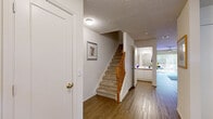 Located at 5001 SW 20th St in Ocala, Florida, this two-story residence offers a well-organized layout across both levels, connected by a carpeted staircase with a warm wood banister. The main level features wood-look flooring throughout the common areas, beginning with a welcoming hallway that leads to the key living spaces. The living room is bright and inviting, with sliding glass doors that open to an outdoor patio area, allowing natural light to flow in and providing views of the surrounding greenery. A dedicated sitting area with hardwood-style flooring offers additional flexible living space. The kitchen is well-equipped with ample white cabinetry accented by wood trim, generous counter space, and a full range, making it both practical and functional. A full bathroom on the main level includes a tub-shower combination, single vanity, and wood-look flooring. Upstairs, the bedrooms are carpeted and filled with natural light from large windows. The primary bedroom connects to a spacious vanity area with a wide white countertop, dual mirrors, and abundant cabinet storage. A second bedroom serves well as a home office, featuring a bright window overlooking the outdoors. Textured ceilings are present throughout portions of the home, adding architectural character to this comfortable multi-level residence.