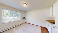 Located at 2221 Hanley Rd in Hudson, Wisconsin, this efficiently designed unit offers a practical and well-organized single-floor layout. The combined kitchen and living room serves as the heart of the space, where white cabinetry, a double-basin sink, electric range, and a full-size refrigerator provide all essential amenities. The kitchen flows seamlessly into the carpeted living area, which is brightened by a large window offering views of mature trees outside. A wall-mounted air conditioning unit and baseboard heating ensure year-round comfort. The textured ceiling and warm wood-toned trim add subtle character throughout. A carpeted hallway connects the main living space to the rest of the unit, with a sliding-door closet providing convenient storage. The full bathroom is cleanly appointed with a white vanity featuring cabinet storage, a large mirror with overhead lighting, hardwood-style flooring, and a shower-tub combination. Neutral wall tones and consistent trim work throughout the unit create a cohesive, understated aesthetic. The space is ideal for those seeking a straightforward, functional layout in a residential setting in Hudson, WI.