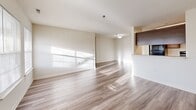 Located at 6406 Paddington Ct in Centreville, Virginia, this three-bedroom, two-bathroom unit offers a well-organized single-floor layout designed for comfortable everyday living. The open-concept living and dining area is a standout feature, showcasing light-toned hardwood-style flooring that runs throughout the common spaces and reflects natural light streaming in through large windows. A raised breakfast bar connects the living area to the galley-style kitchen, which is outfitted with rich dark brown cabinetry, light countertops, a double sink, and black appliances including a full-size refrigerator and dishwasher. The three bedrooms are carpeted and filled with natural light from individual windows. The spacious primary bedroom offers generous room and direct access to a closet. The secondary bedrooms each feature their own closet storage, with one showcasing double doors for added capacity. The two bathrooms provide functional layouts — one with a walk-in shower stall and the other with a full soaking tub and shower combination, both finished in clean white. Three closets throughout the unit offer plentiful storage. The unit's neutral color palette and clean finishes create a bright, move-in-ready atmosphere throughout.
