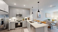 Located at 526 Vistera Blvd in Venice, FL, this 1-bedroom, 1-bathroom unit offers a well-designed open-concept floor plan that seamlessly integrates the living, dining, and kitchen areas. The kitchen is a standout feature, outfitted with gray shaker-style cabinetry, white quartz countertops, a subway tile backsplash, stainless steel appliances, and a peninsula with pendant lighting that doubles as a casual dining bar. Light wood-tone flooring runs throughout the main living areas, enhancing the bright, airy atmosphere created by multiple windows. The living room benefits from ample natural light through large windows and a ceiling fan, providing a comfortable, open feel. The bedroom offers a serene retreat with carpeted flooring, dual windows that invite natural light, and a ceiling fan. Three closets provide generous storage throughout the unit. The bathroom features a full tub and shower combination with tile surround, a vanity with under-mount sink, and matching light wood-tone flooring. Additional conveniences include a dedicated laundry area and a private balcony. The overall design is clean and contemporary, with a neutral color palette that creates a cohesive, modern aesthetic throughout.