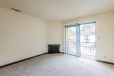 This single-floor residential unit offers a well-organized and functional layout across several distinct areas. The living room serves as the central gathering space, finished with plush wall-to-wall carpeting, clean white walls, and a textured ceiling. A sleek built-in fireplace anchors one corner of the room, while a sliding glass door lined with vertical blinds opens to a private balcony, inviting natural light and views of the surrounding neighborhood. A thermostat on the wall provides convenient climate control.

The kitchen is efficiently designed with white cabinetry offering ample storage, dark countertops, and a full suite of white appliances including an electric range and refrigerator. Light wood-look flooring and a window above the counter complete the space with a clean, practical feel.

The bedroom is generously sized, featuring soft carpeting, a large window that draws in natural light, and a dark wood closet. It connects conveniently to the bathroom, which is outfitted with a tub and shower combo featuring marble-patterned surround walls, a single vanity with mirror, and wood-look flooring.

The entryway transitions smoothly from the front door into the main living areas, tying the layout together with a cohesive, neutral palette throughout.