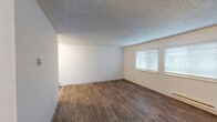 Located at 1706 22nd Way NE in Auburn, Washington, this one-bedroom, one-bathroom unit offers a practical and well-organized single-floor layout. The living room is generously sized, featuring durable wood-style flooring, neutral wall tones, textured ceilings, and dual windows that allow natural light to fill the space. A baseboard heating unit ensures year-round comfort. The combined kitchen and dining area is efficiently designed with dark cabinetry, white countertops, a stainless steel sink, and black appliances including an electric range. A ceiling fan with light fixture serves the dining space, which also features wood-style flooring. The bedroom is a comfortable retreat finished with plush carpeting, a closet, and sliding glass doors that open to a private balcony overlooking a green outdoor area, bringing in abundant natural light. An additional closet in the hallway provides extra storage. The bathroom includes a full tub and shower combination with clean white finishes and chrome fixtures. An in-unit laundry area adds everyday convenience. Overall, the space presents a clean, functional, and bright atmosphere suited for comfortable everyday living.