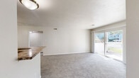 Located at 1 Cedarwood Way in Newport News, Virginia, this two-bedroom, one-bathroom single-floor home offers a practical and comfortable layout. The open-concept living and dining area is carpeted throughout and filled with natural light, anchored by a sliding glass door that opens to an outdoor view of greenery. The kitchen is well-appointed with dark cabinetry, granite-style countertops, a peninsula with bar seating, and wood-look vinyl flooring, and it connects seamlessly to the living area for easy entertaining. Two bedrooms provide comfortable accommodations; the primary bedroom is generously sized and features multiple closets, while the second bedroom includes a bright window with outdoor views and plush carpeting. Both rooms offer a clean, neutral palette. The full bathroom is finished with a dark wood vanity, white countertop, a full tub/shower combo, and wood-look flooring. Additional features include multiple hallways for convenient circulation, four closets for ample storage, and an in-unit laundry area. Throughout the home, neutral tones, clean lines, and consistent finishes create a cohesive and move-in-ready atmosphere.