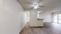 Located at 444 S Kingsley Dr in the Koreatown neighborhood of Los Angeles, this one-bedroom, two-bathroom unit offers a well-organized single-floor layout with consistent wood-style flooring throughout. The living room serves as the centerpiece of the home, highlighted by a striking floor-to-ceiling stone fireplace that adds a bold architectural element and a sliding glass door that opens to an outdoor space, allowing natural light to fill the room. A ceiling fan completes the comfortable atmosphere. The open kitchen flows directly from the living area and features a peninsula-style breakfast bar with a dark countertop, white cabinetry, a built-in sink, and a range. Recessed lighting and a ceiling fan brighten the space. The spacious primary bedroom includes a ceiling fan, a large sliding-door closet with built-in shelving, and wood-style flooring, offering ample storage and comfort. A window with vertical blinds provides natural light. Both bathrooms are clean and functional; one features a full tub-shower combo with sliding glass doors, a single-sink vanity with white cabinetry, a large mirror, and wood-style flooring. The textured ceilings are consistent throughout the unit, lending a classic Los Angeles residential character to the overall design.