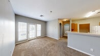 Located at 605 Highland Ridge Dr in Manhattan, Kansas, this single-floor residence offers a well-designed layout with a comfortable, functional flow throughout. The living area is spacious and bright, featuring plush carpeting, neutral gray walls, and a set of French doors that invite natural light while providing access to the outdoors. A charming arched doorway connects the living space to the entryway, adding an architectural detail that enhances the open feel of the floor plan. A kitchen bar counter separates the living and kitchen areas seamlessly.

The kitchen is fully equipped with warm honey-toned cabinetry, light countertops, and white appliances including a refrigerator, range, microwave, and dishwasher. Light tile flooring and ample cabinet storage make this a practical and inviting space for cooking.

The bedrooms are carpeted and filled with natural light through large windows. Each room offers closet space, with at least one bedroom featuring a generously sized closet with wire shelving. The bathrooms are finished with warm wood vanities, light countertops, large mirrors, and tub-shower combinations. A dedicated in-unit laundry area houses a full-size washer and dryer with overhead wire shelving for added storage convenience.